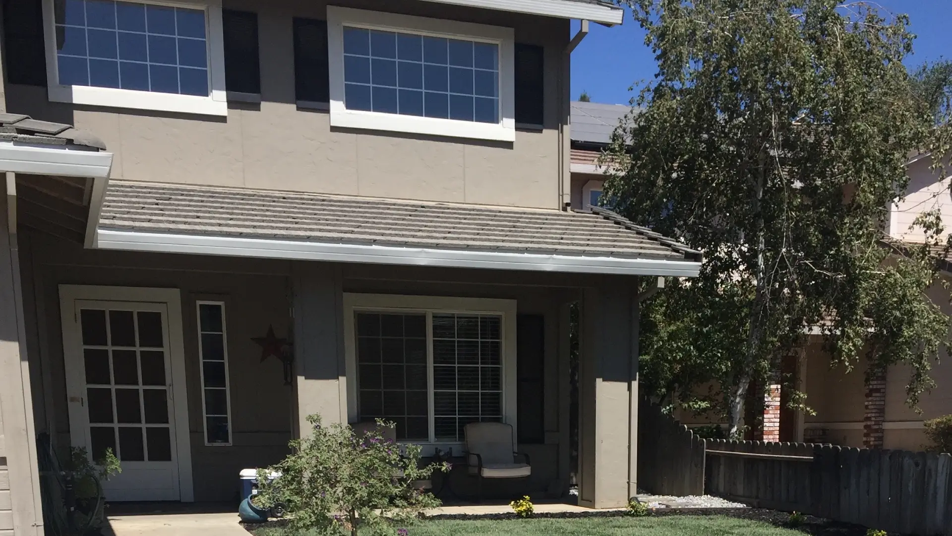 Side view of a modern grey home showing a paved driveway and partial yard.