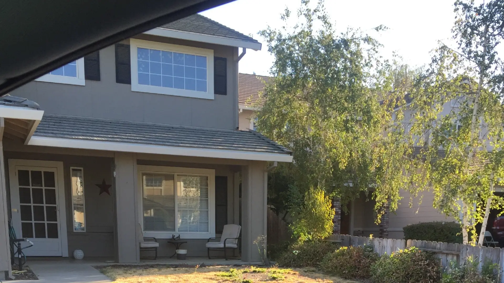 Front elevation of a grey family home with a small porch and manicured lawn.